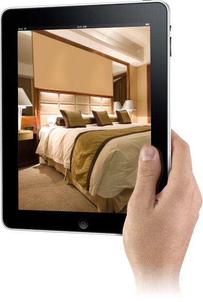 Una mano sorregge un iPad su cui è raffigurata una stanza di hotel.
